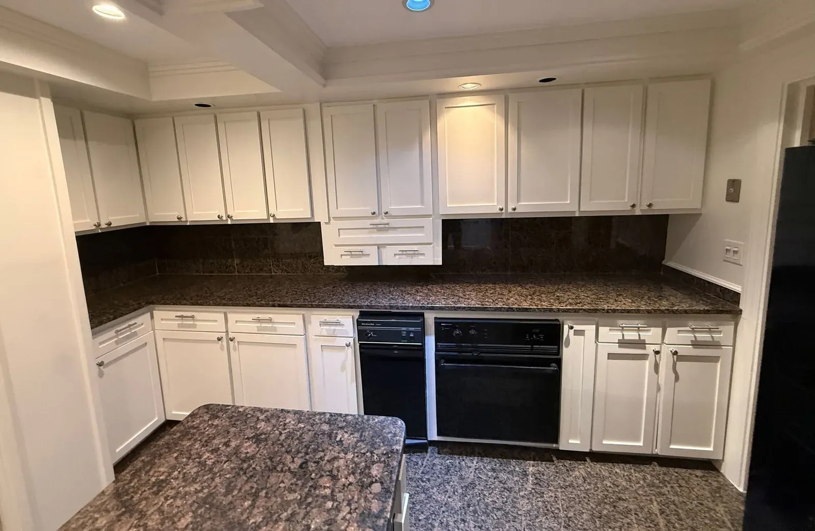 Renovated kitchen with white cabinetry and granite worktops