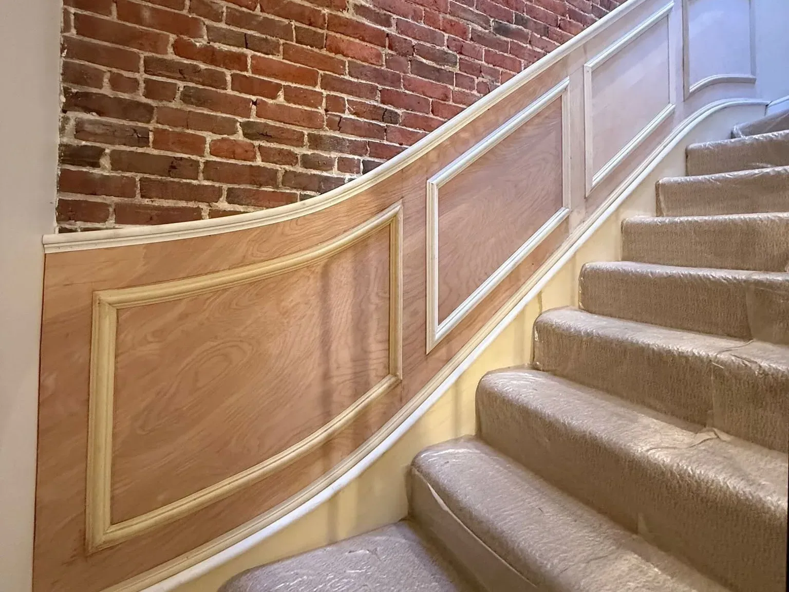 New panelled wainscoting following a curved stair beside exposed brick