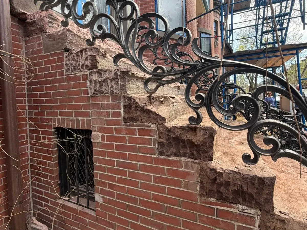 Brick facade and ironwork being rebuilt beneath a South End stoop